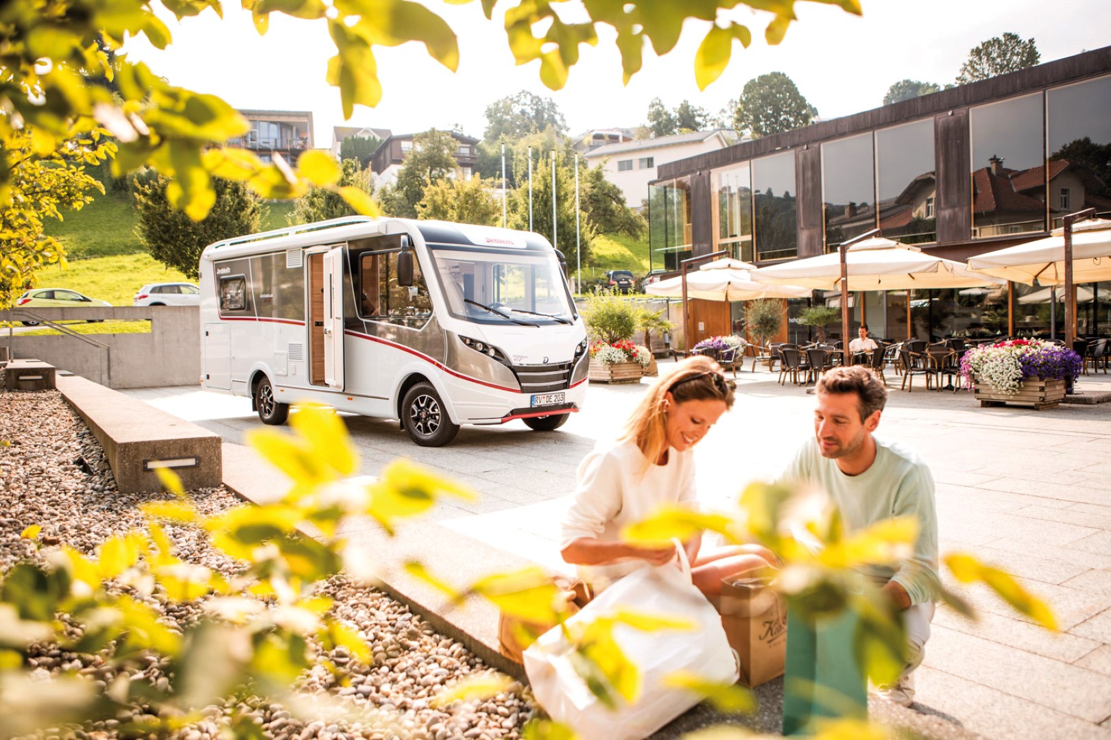 Pärchen beim Frühstück, im Hintergrund ein Wohnmobil